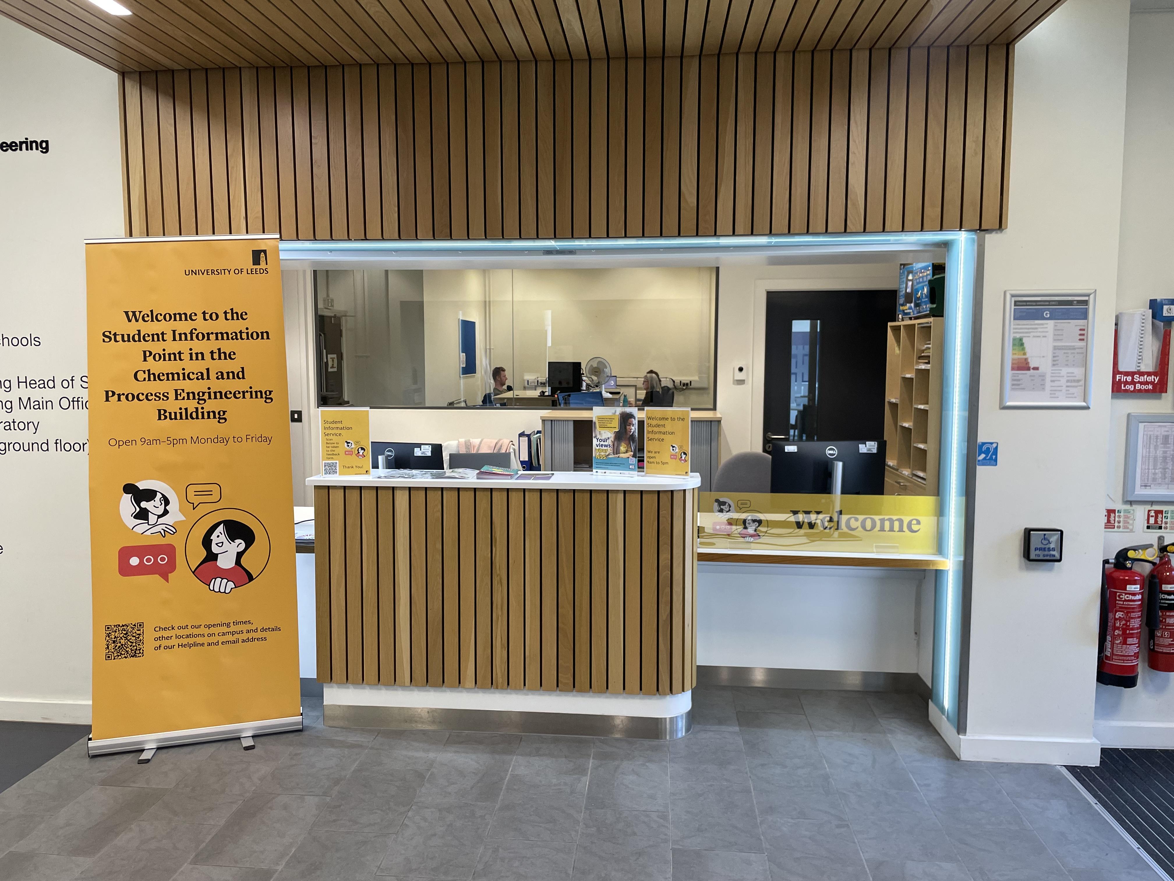 A  photo of an information desk. There is a counter and a poster next to it.