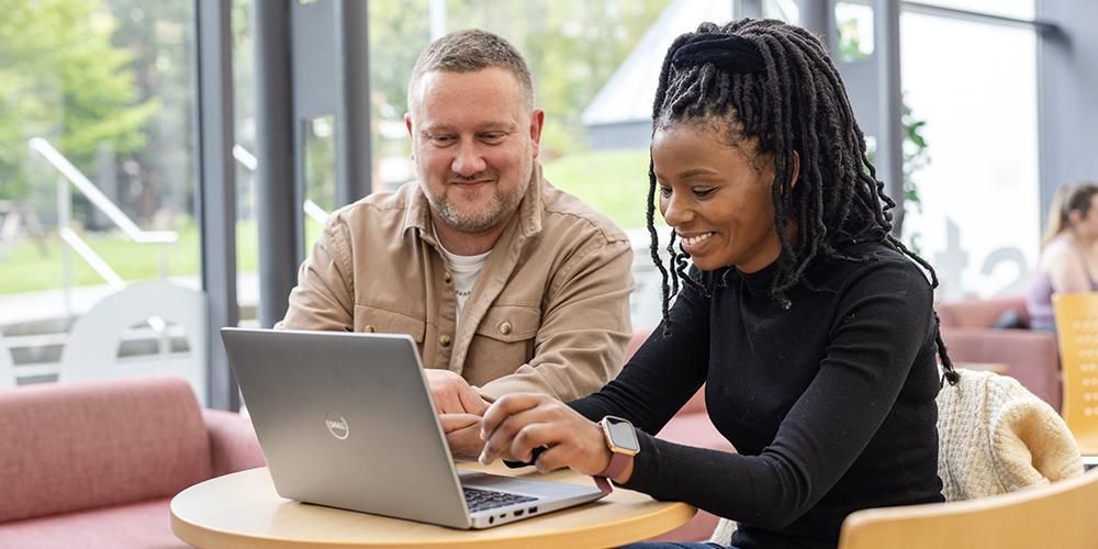 Two people sitting working together on a laptop