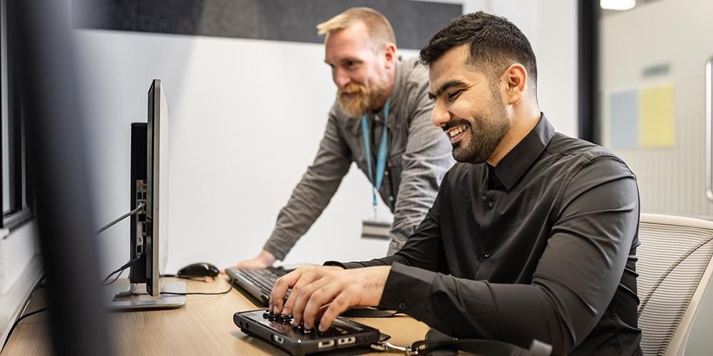 Staff member supporting a student using assistive technology in the library