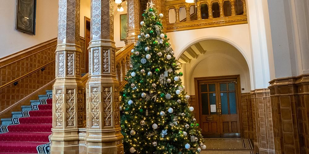 Christmas tree next to grand pillars and a staircase in the Great Hall entrance