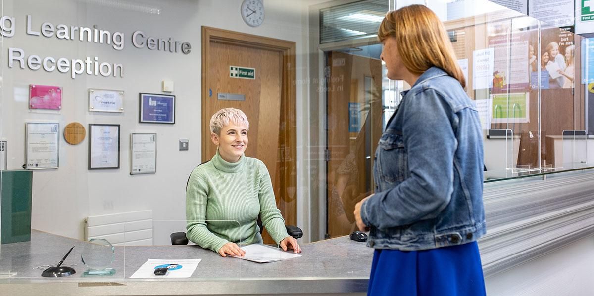 A staff member helping a student at the Lifelong Learning Centre reception