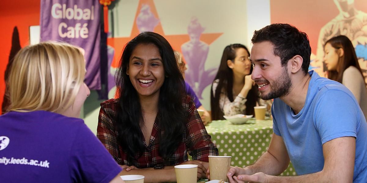 Three students chatting at a table at Global Café