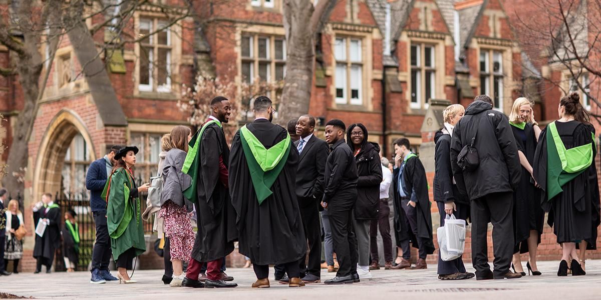 Graduates in gowns and guests standing and talking outside Clothworkers Court on graduation day