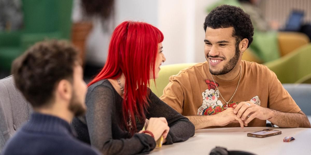 A student chatting with an experienced peer in a study space on campus.