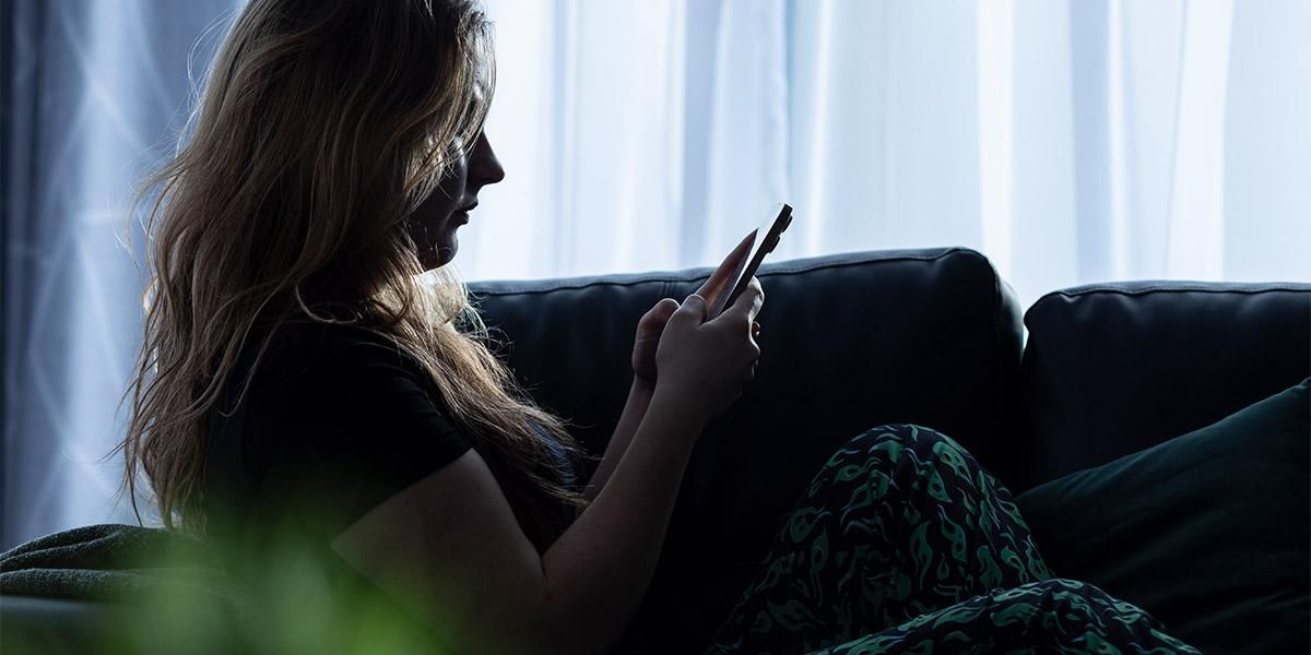 A person sitting on a couch looking at a mobile phone