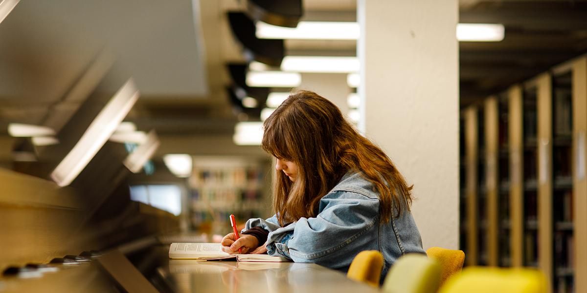 Student writing at a desk in the Edward Boyle Library