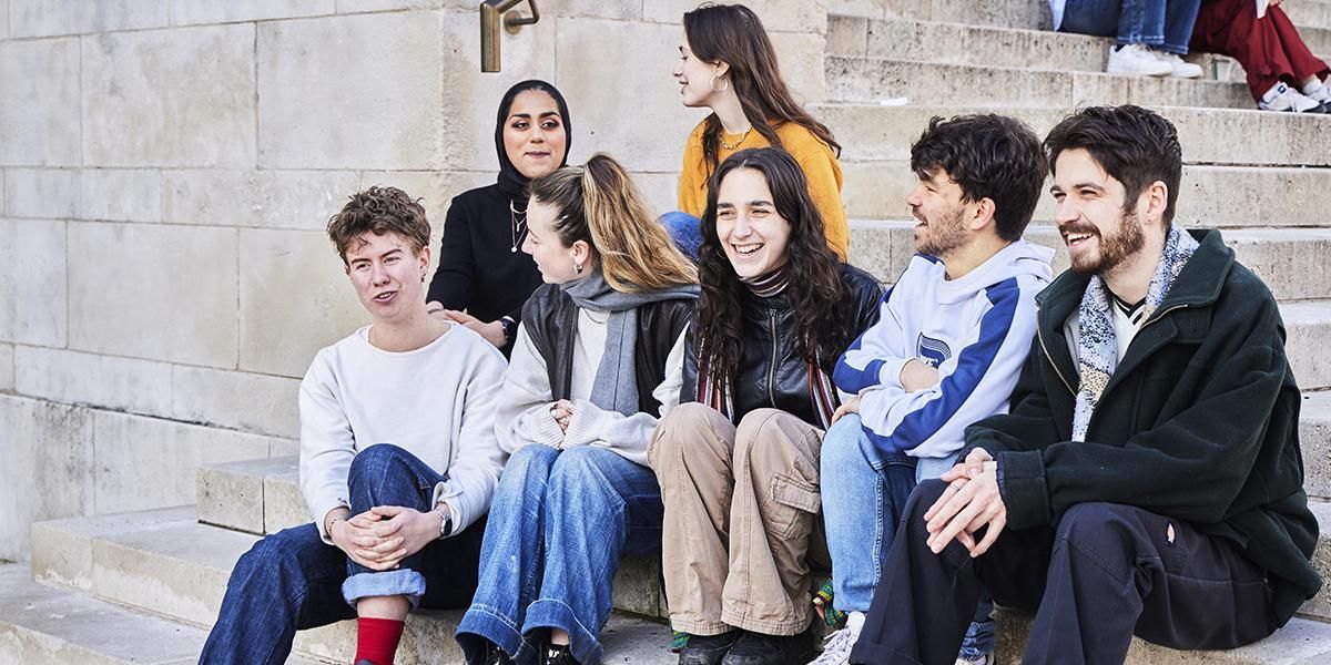 Student action for refugees volunteers sat talking on the Parkinson Building steps