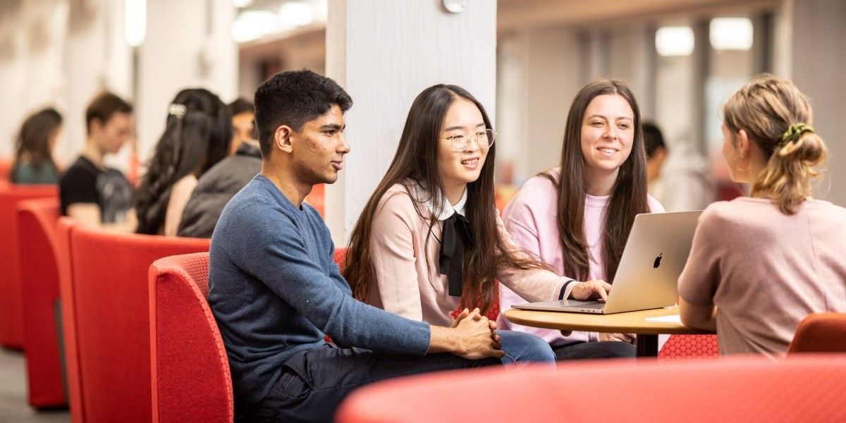 A group of a students sat around a table socialising.