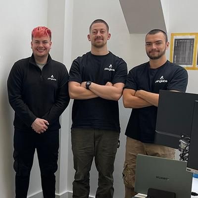 Timur Gok, founder of Ping Technology Labs, stands smiling with two colleagues with arms folded