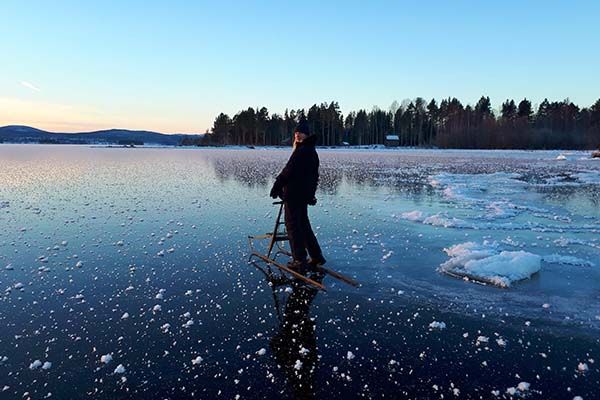 A student walking across a frozen lake using a walker.