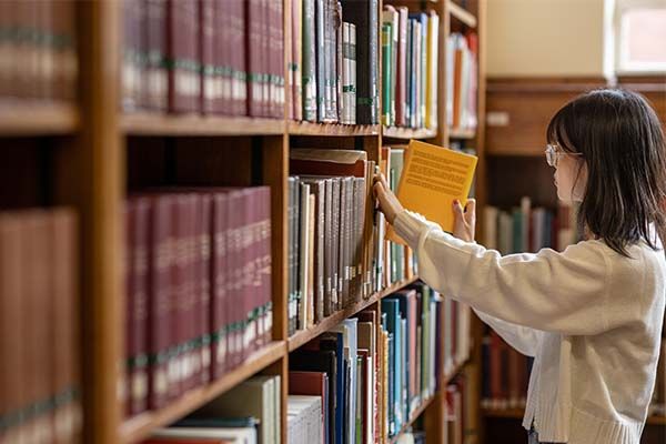 A student places a book back on the library shelves.