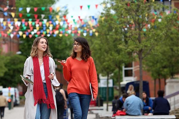 Two postgraduate students walking outside the students' union building.