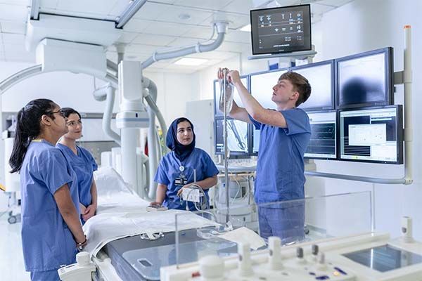 Three healthcare and medical students work together in a cath lab.