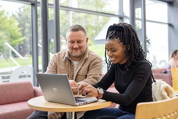 Two people sitting working together on a laptop