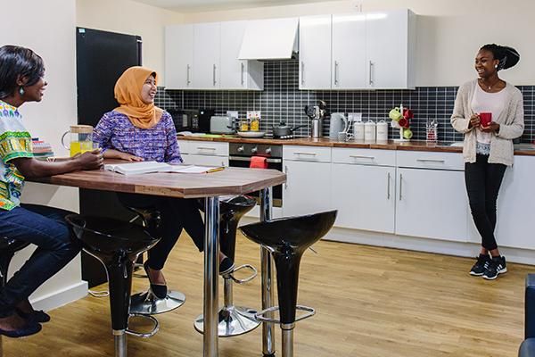 Three students chatting in a kitchen in student accommodation