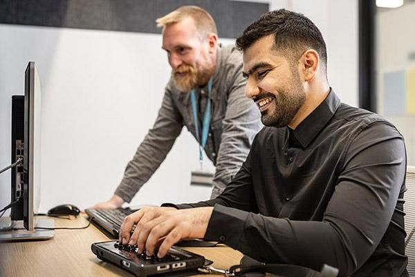 Staff member supporting a student using assistive technology in the library