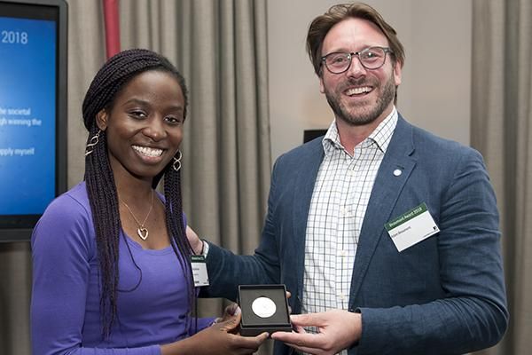 A student winner of the Beaumont Award holding a medal standing with Professor Adam Beaumont