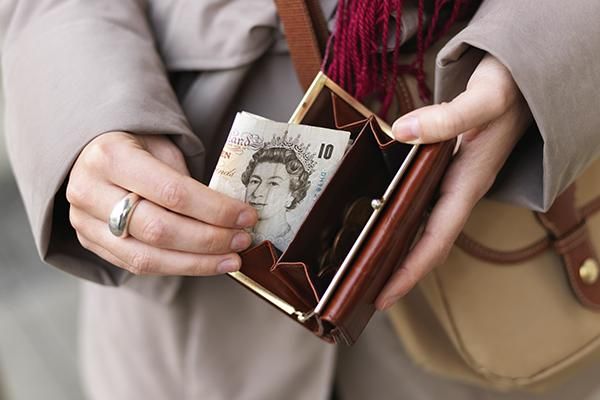 Hands putting a £10 note into a purse