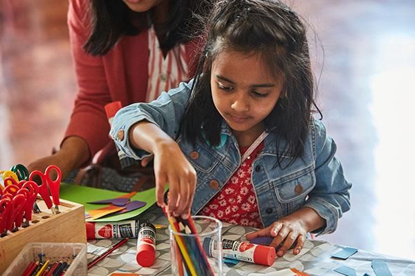 Child doing crafts with pencils and glue sticks at Be Curious