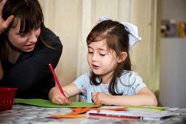 Child drawing with coloured pencils at Be Curious supported by a parent