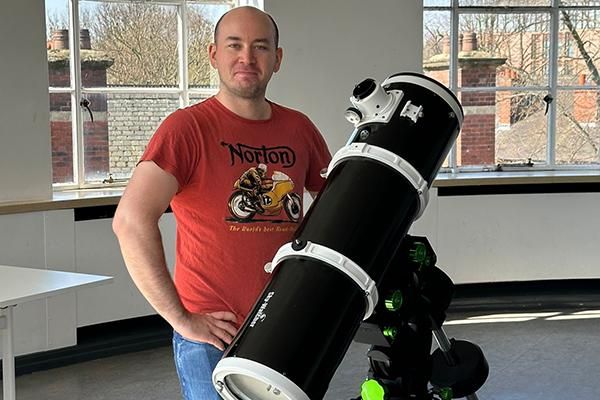 Craig Barningham next to a telescope