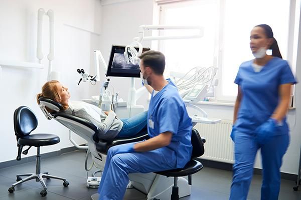 Two dentists in a dental surgery with a patient lying on a bed