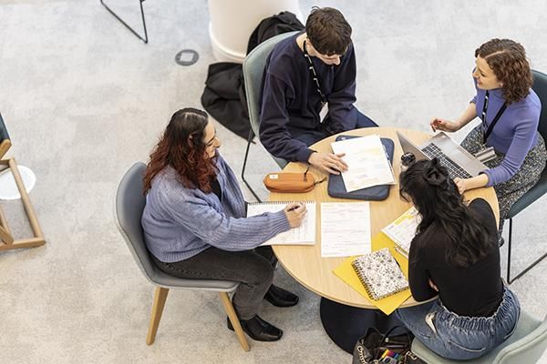 Four students working at a circular table