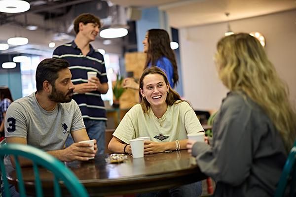 Three students sitting around a table chatting at Global Café.