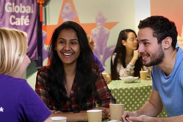 Three students chatting at a table at Global Café