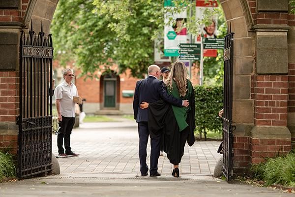 Graduate and guest embracing on graduation day