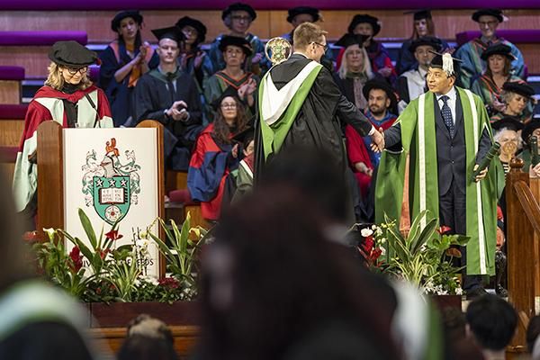 Graduate shaking hands with presiding officer Hai-Sui Yu at a graduation ceremony