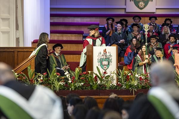 Graduand walking up to presiding officer on the stage at graduation.