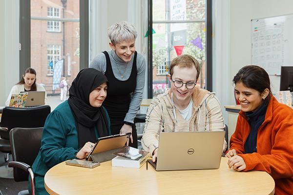A Lifelong Learning Centre staff member working with three foundation year students sitting around a laptop