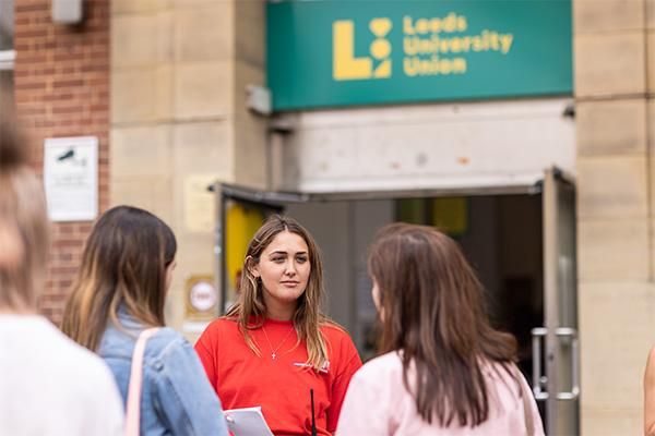 Student ambassadors welcome visitors outside Leeds University Union during the June 2022 Open Day, creating a warm, inviting atmosphere.