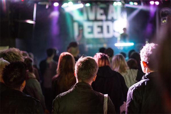A group of people standing in a club watching a performance.