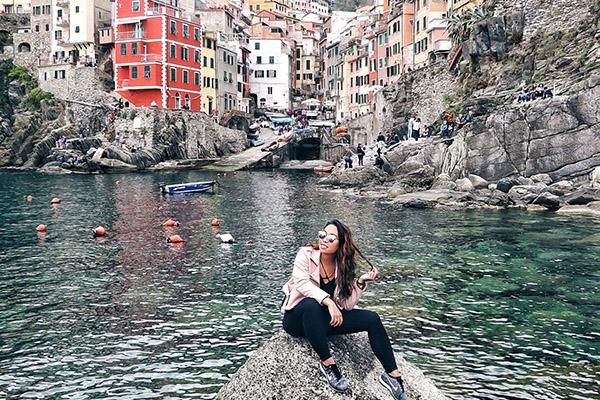 A student studying abroad in Italy surrounded by colourful houses and water.