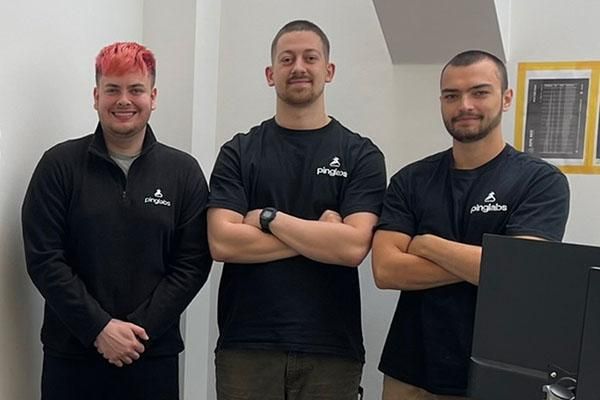 Timur Gok, founder of Ping Technology Labs, stands smiling with two colleagues with arms folded