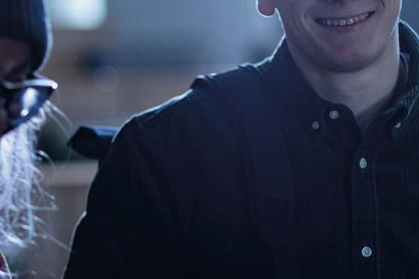 Close up of a person slightly smiling wearing a dark button up shirt