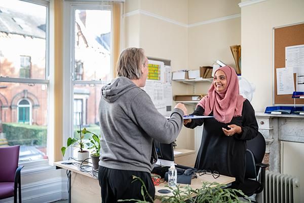 Staff member handing a student a clipboard in an office