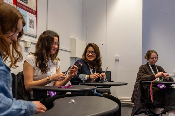 Students sitting at tables at the  Student sustainability research conference crafting using scissors