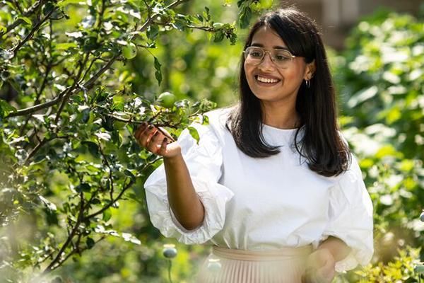 Student in Sustainable Garden surrounded by leaves