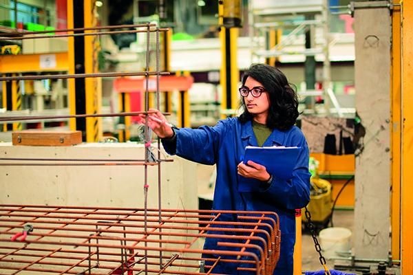 Student on construction site inspecting the metal frame of a structure