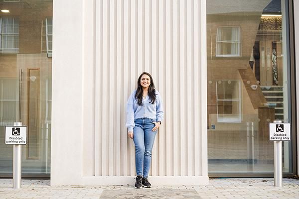 Student outside Esther Simpson building near two disabled parking spaces