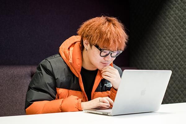 Student sitting in a booth smiling using a laptop