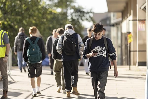 Student using phone walking on campus near the Edward Boyle Library