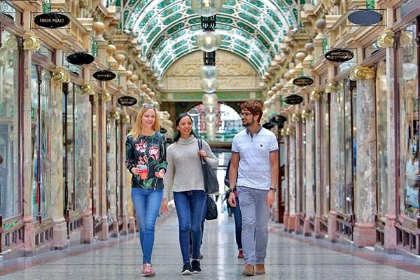 Three students walking in the Victoria Quarter, a shopping centre in Leeds