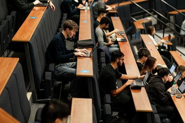 Rows of students working on laptops in a lecture theatre