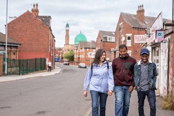 Three students walking in Hyde Park area of Leeds. A mosque is in the background