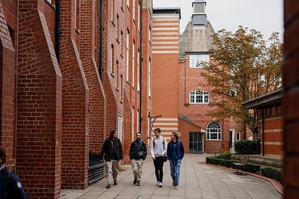 Three students walking near Clothworkers' Building on campus