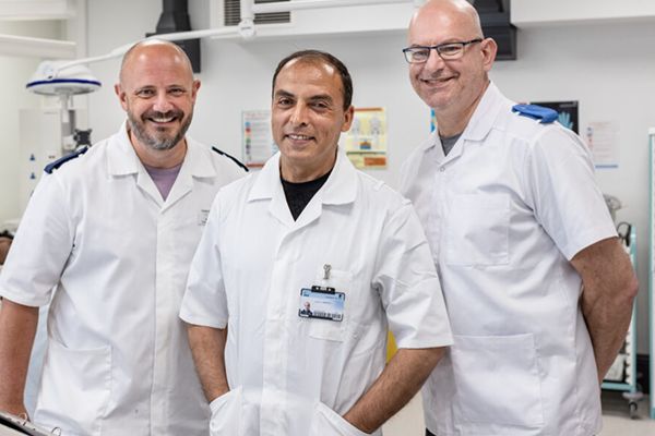 Three nursing associate apprentices wearing white scrubs in a hospital